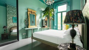 A bedroom with a large bed, a chandelier, a mirror, and a plant. - Belsize Park Gardens by onefinestay (London)