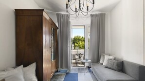Een moderne woonkamer met een grijze bank, een houten garderobe, een eettafel met stoelen en uitzicht op het omliggende landschap.