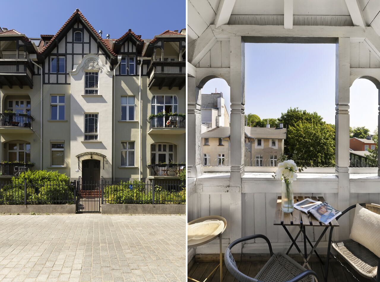 A multi-story building with balconies and a covered outdoor seating area with chairs and a table.