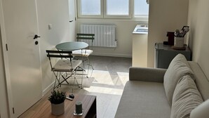 Una sala de estar moderna con un sofá, una mesita y un ventanal con vistas a edificios.