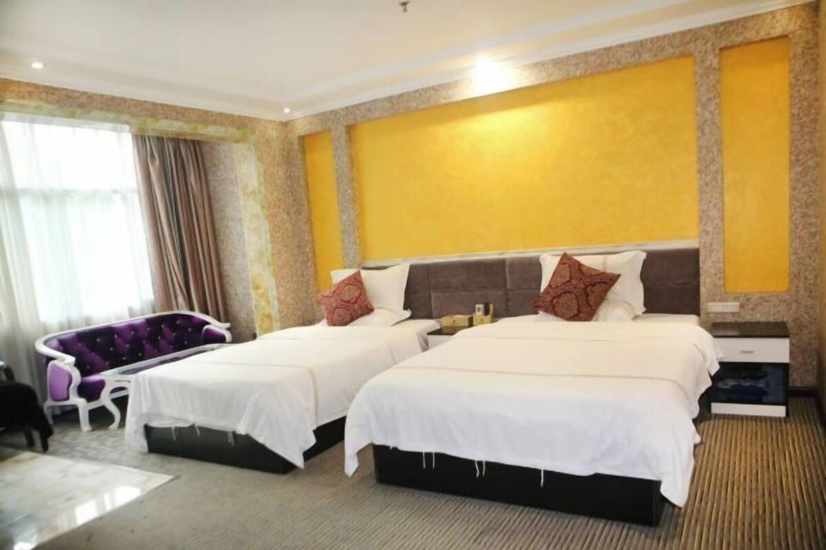 A hotel room with two beds, a sofa, and a nightstand.