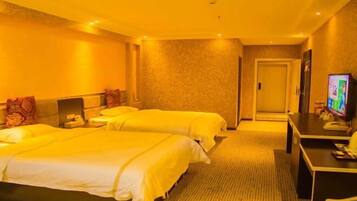 A hotel room with two beds, a desk, a television, and a door.
