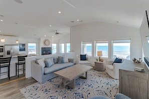 Uma sala de estar moderna com um sofá, uma mesa de centro e vista para o oceano.