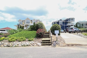 A residential area with houses, a paved driveway, and a bicycle. - Sun Realty cozy 4BR oceanside Duck cottage just 300' to the beach (Duck)