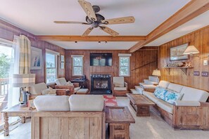 Ein gemütliches Wohnzimmer mit Holzwänden, einem Kamin und einem Deckenventilator.