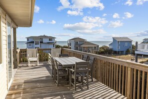 Enjoy a meal on the deck with a view of the ocean and surrounding houses.