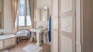 Un bagno con un lavandino bianco, uno specchio e una finestra con tende.