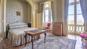 Una stanza con un letto, un tavolo in legno, una cassettiera e una sedia.
