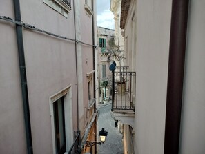 A narrow alleyway between buildings with a person walking down. - 2-Bedroom Apartment in Syracuse (Siracusa)