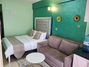 A bedroom with a bed, a sofa, a small table, and decorative wall elements.