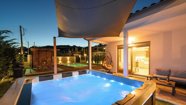 Un bain à remous doté d’une terrasse en bois et d’un espace salon abrité.
