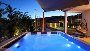 Un bain à remous avec vue sur une piscine et une terrasse en bois.