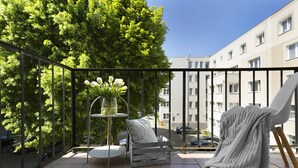A balcony with a round table, two chairs, a potted plant, and a blanket. - Elite Apartments Wesola Economy (Gdansk)