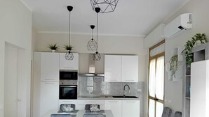 Uma cozinha moderna com armários brancos, uma ilha central e iluminação pendente.