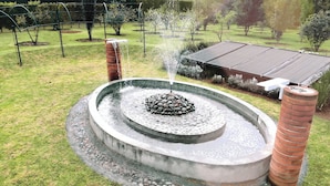 A circular water feature with a central rock arrangement and two brick pillars. - Eucaliptos Med Spa (Zitácuaro)