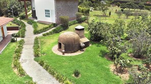 A garden with a stone structure, a pathway, and a white building. - Eucaliptos Med Spa (Zitácuaro)