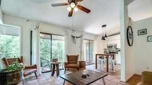 A spacious living area with a wooden coffee table, leather chairs, and a ceiling fan. - Downtown Treetop Hideaway- SXSW, 6th St, UT Campus

 (Austin)