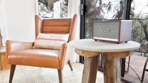 A brown leather chair with a cushion, a small round wooden table, and a Marshall speaker on the table. - Downtown Treetop Hideaway- SXSW, 6th St, UT Campus

 (Austin)