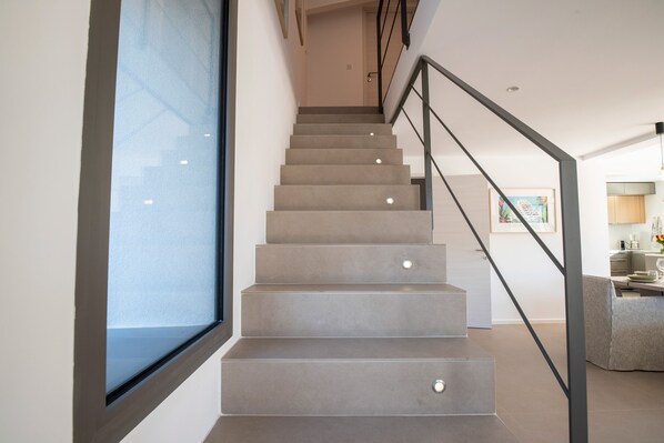 A modern staircase with a minimalist design, leading to a well-lit interior space.