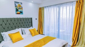 A neatly made bed with a tufted headboard, white bedding, and two yellow pillows. - Lulu Homes at Gatundu Heights (Nairobi)