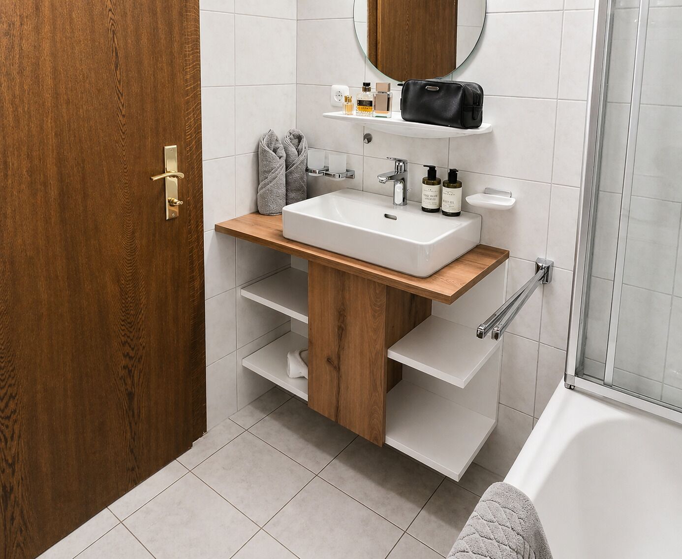 Un baño con tocador de madera, lavamanos blanco y zona de ducha.