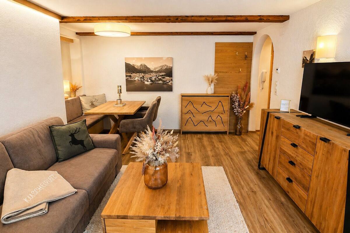 Un salon chaleureux avec un canapé, une table basse, un téléviseur, un meuble en bois et un coin repas comprenant des chaises et une table.