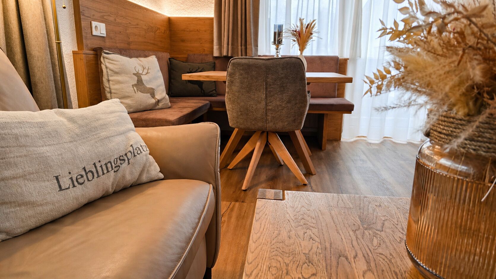 A cozy room with a leather sofa, a wooden dining table, and a chair with wooden legs.