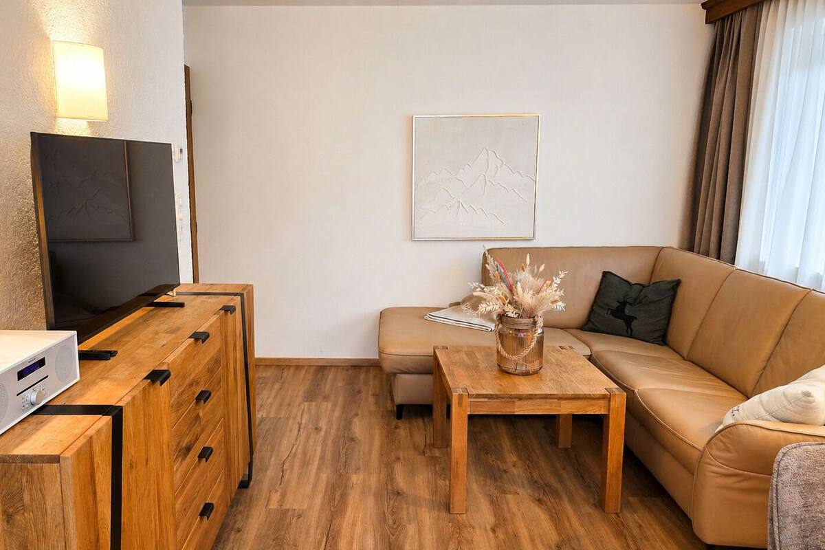 Un salon moderne avec un meuble TV en bois, un téléviseur à écran plat, un canapé, une table basse et une lampe fixée au mur.