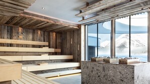 Een moderne keuken met houten balken, een groot eiland en uitzicht op besneeuwde bergtoppen.