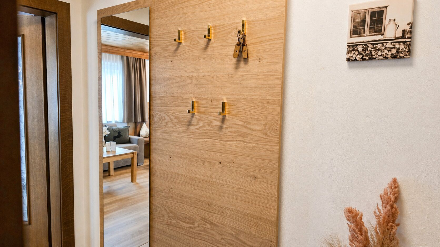 A wooden door with a mirror, a wall-mounted shelf with a picture, and a door frame.