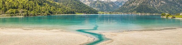 Un lago con un centro turquesa transparente, rodeado de montañas boscosas.