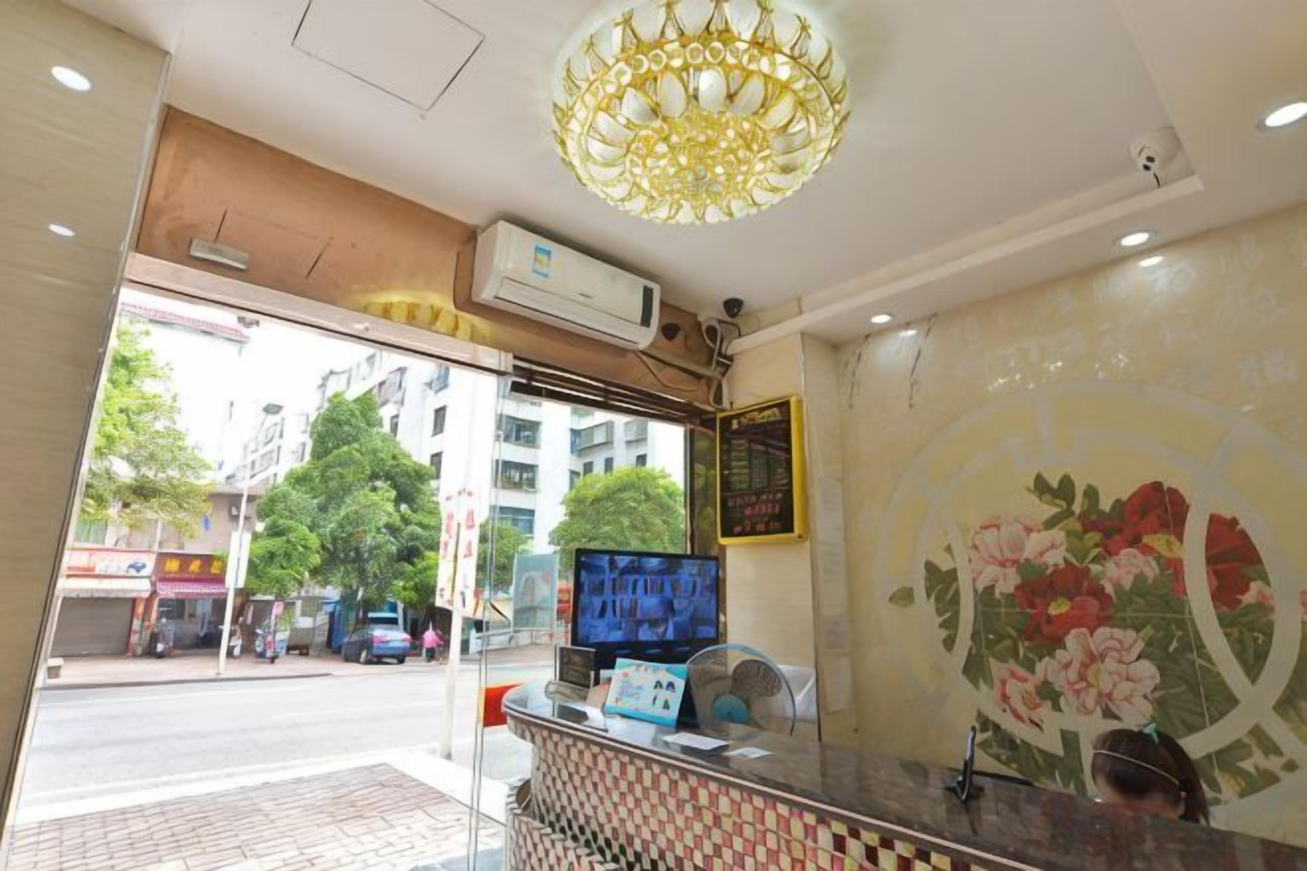 A hotel reception area with a television, a decorative wall, and a view of the street outside.