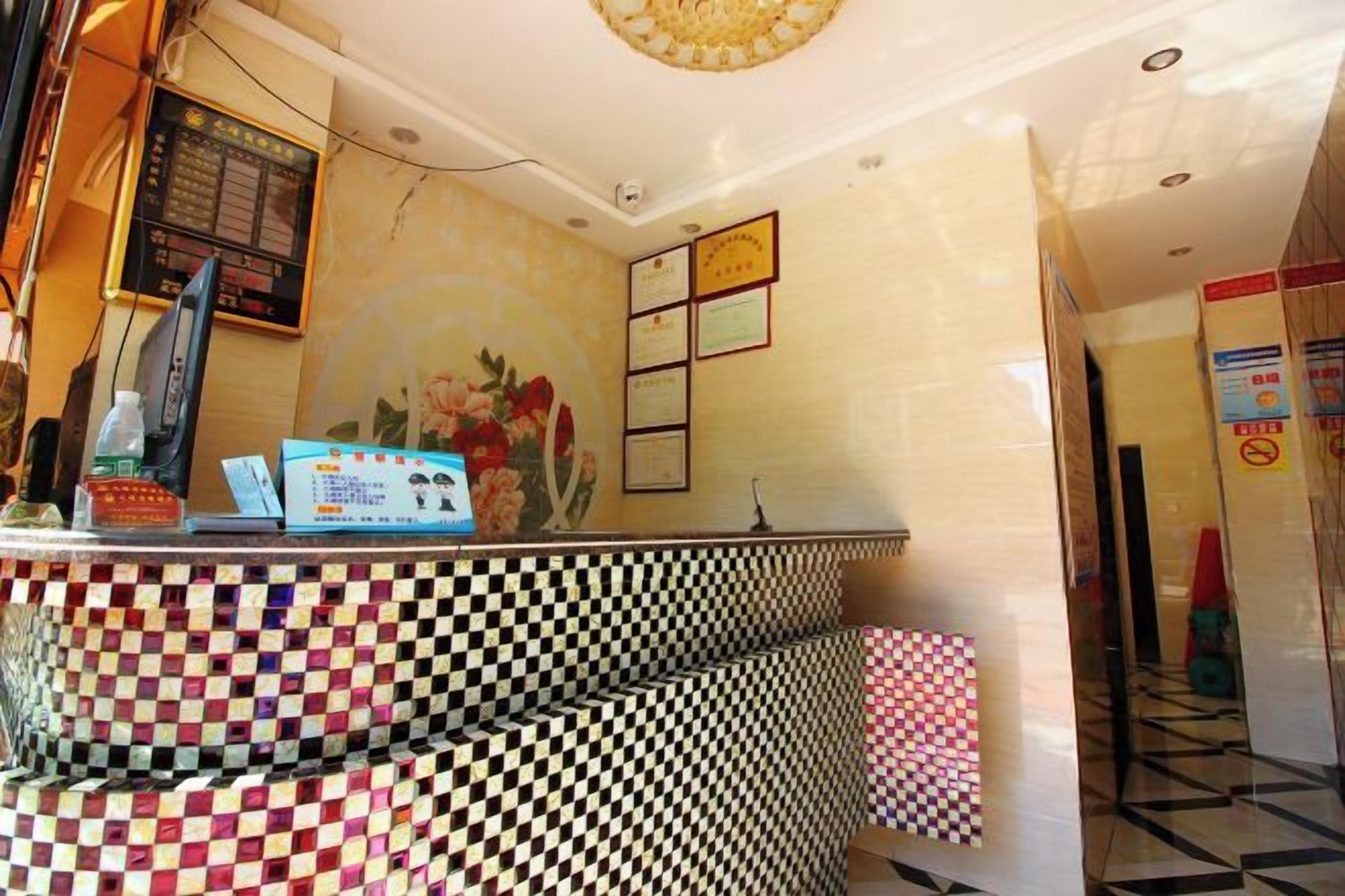 A reception area with a checkered floor, a reception desk, a wall-mounted screen, and framed pictures.