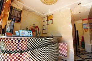 A reception area with a checkered floor, a reception desk, a wall-mounted screen, and framed pictures.