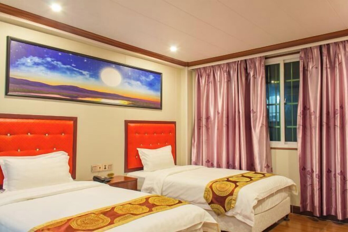 Une chambre d’hôtel avec deux lits, une peinture représentant un ciel étoilé et des rideaux roses.