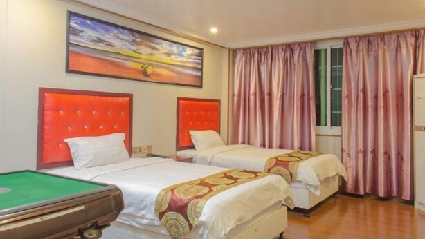 Een hotelkamer met twee bedden, een pooltafel en een schilderij aan de muur.