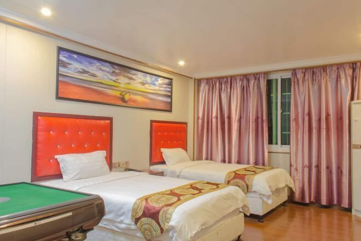 Une chambre d’hôtel avec deux lits, une table de billard et un tableau au mur.