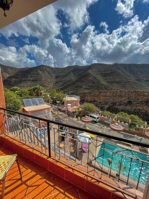 Un balcon avec vue sur une piscine, une montagne et une installation de panneaux solaires.
