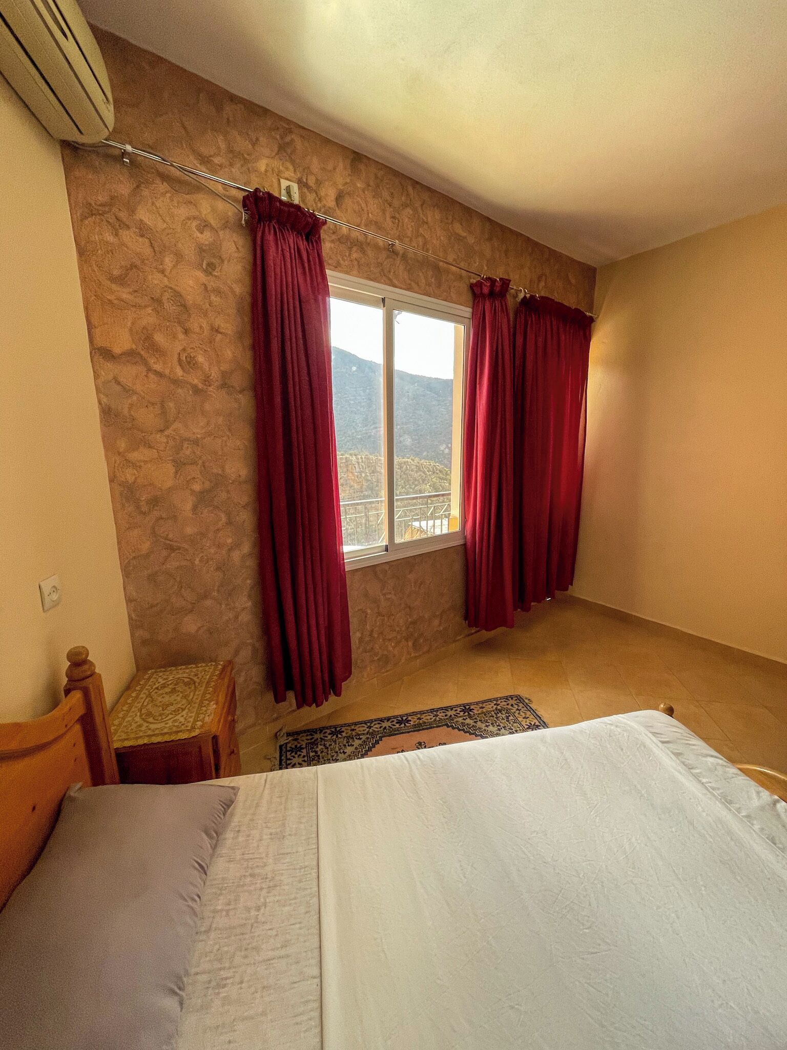 Une chambre à coucher avec un lit, une petite table et une fenêtre avec des rideaux.