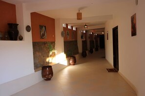 Un couloir doté d’un sol carrelé, d’un mur en bois et d’un luminaire suspendu.