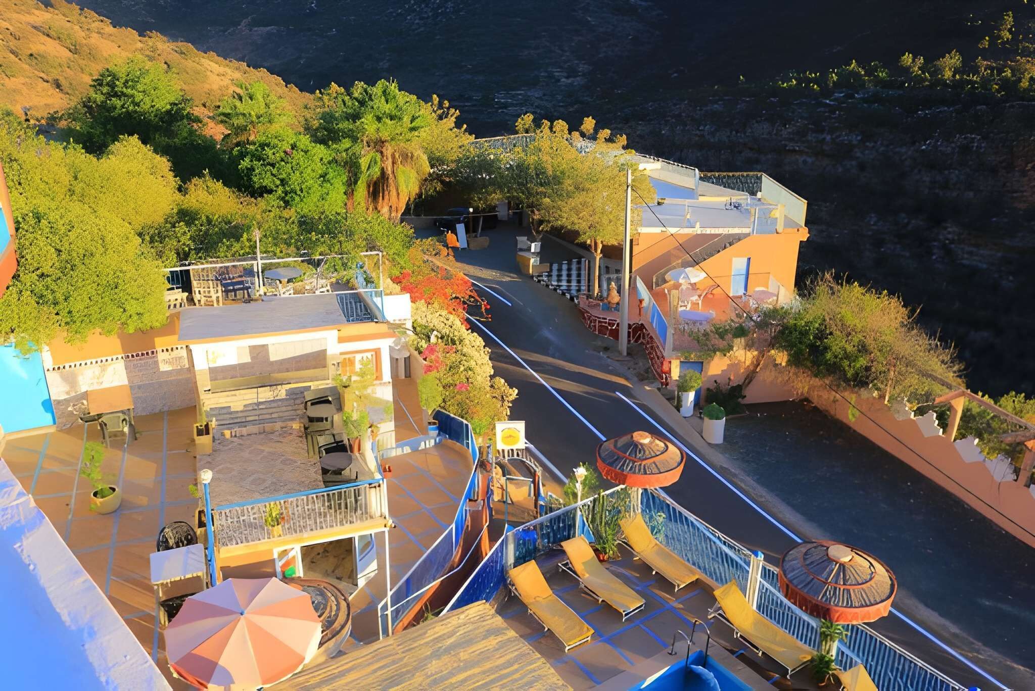 A coastal hotel with a pool, outdoor seating, and a view of the sea.