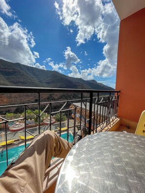 Un balcon avec vue sur une piscine et des montagnes.