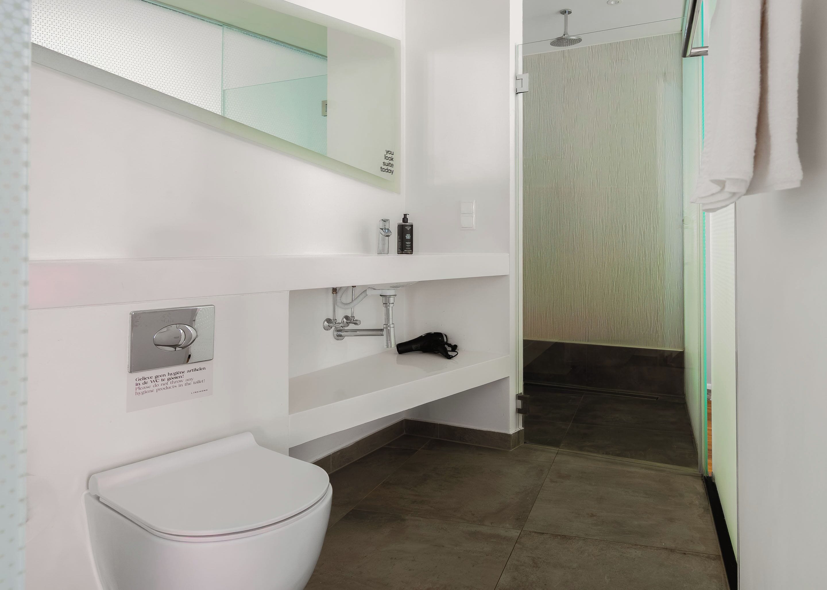 A modern bathroom with a white sink, a toilet, and a shower area.