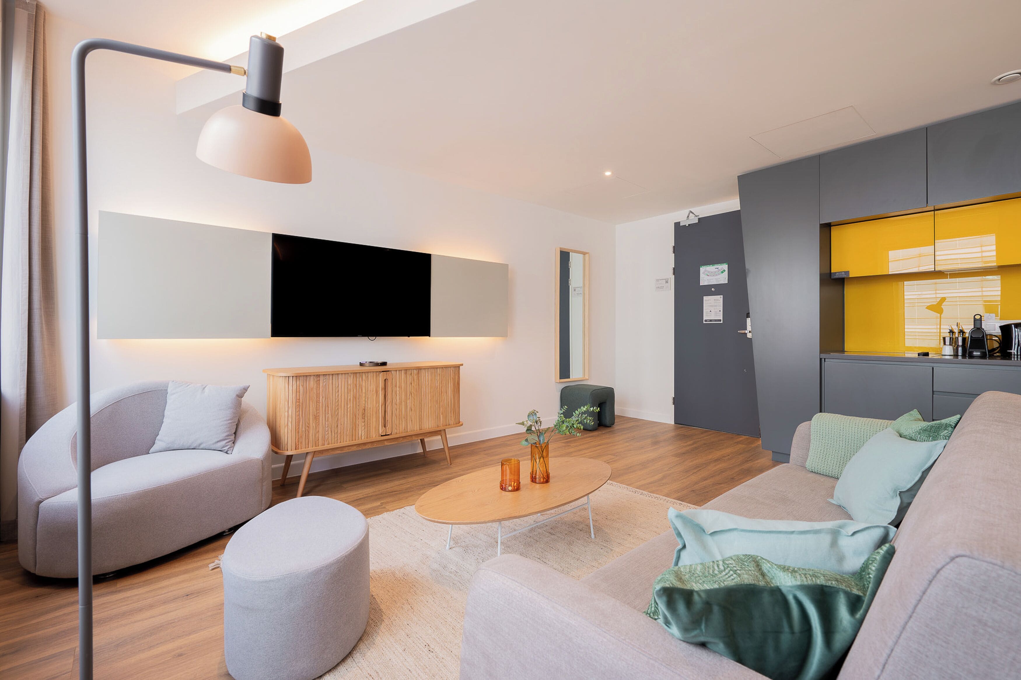 Una sala de estar moderna con un sofá, reposapiés, mesa de centro y un televisor de pantalla plana montado en la pared.