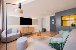 Una sala de estar moderna con un sofá, reposapiés, mesa de centro y un televisor de pantalla plana montado en la pared.