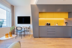 Una cocina moderna con una isla integrada, un televisor de pantalla plana montado en la pared y una zona de comedor con una mesa pequeña y sillas.