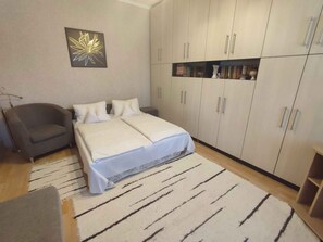 A bedroom with a bed, a chair, a wardrobe, and a decorative wall piece.