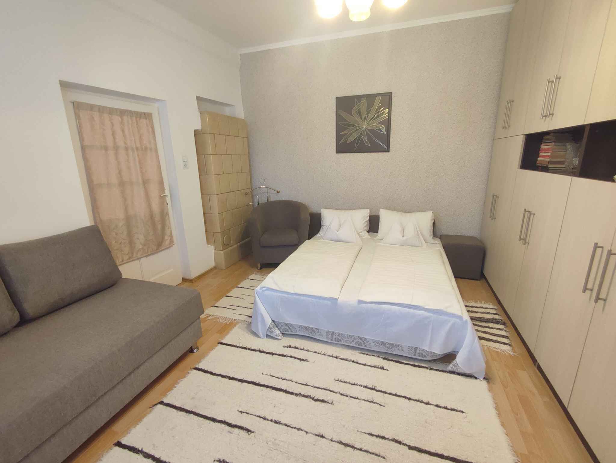 Quarto com cama, sofá, guarda-roupa e um quadro na parede.