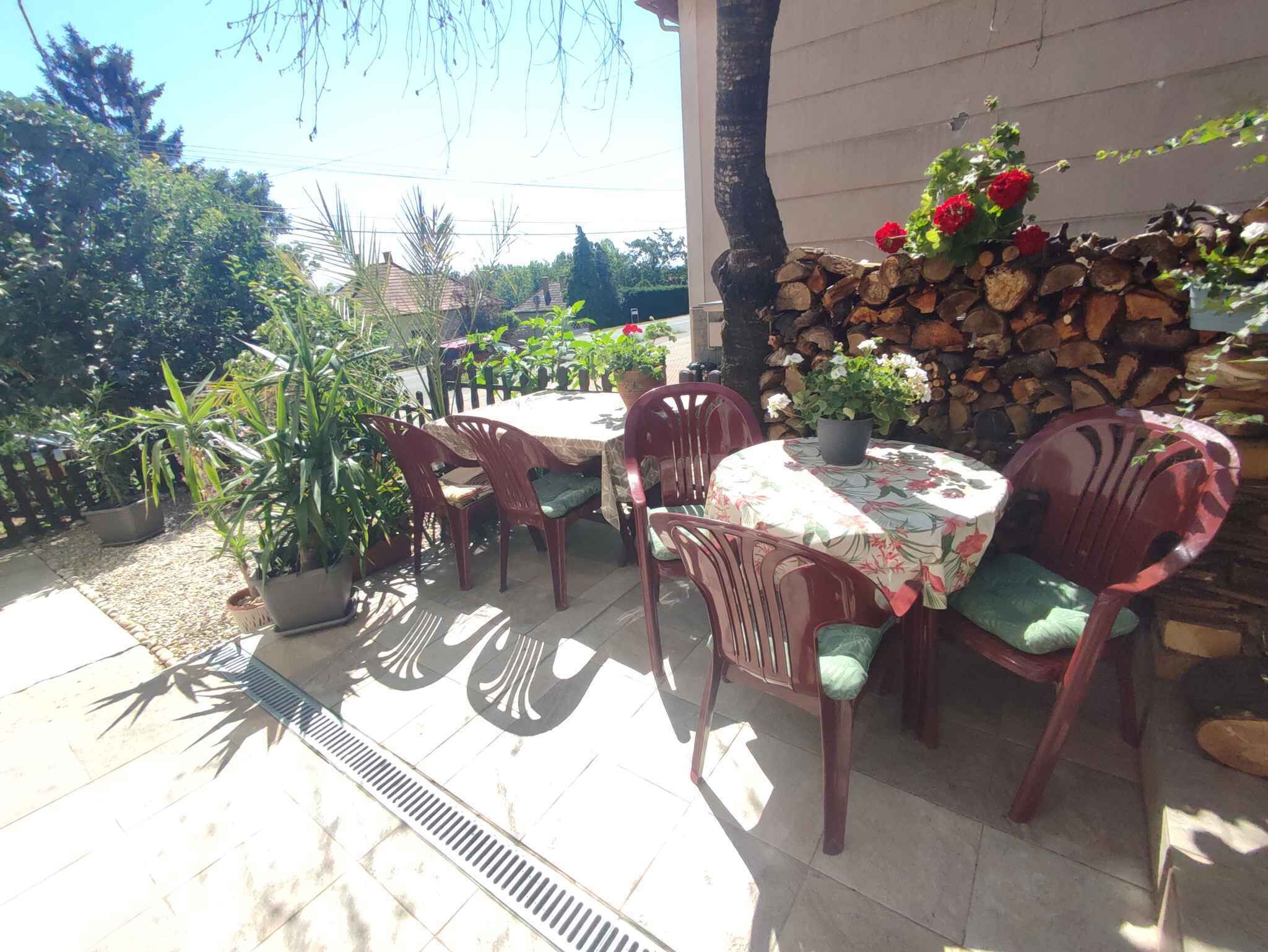 Une terrasse extérieure avec une table ronde, quatre chaises et un pot de fleurs.