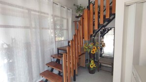 Una escalera de madera con barandilla de metal, que lleva a un rellano con una planta en maceta.